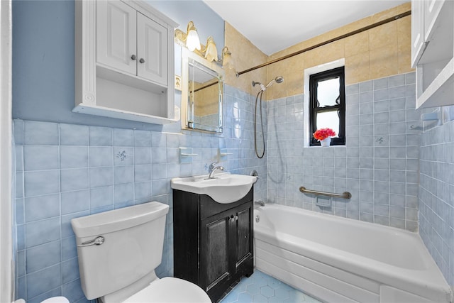 full bathroom with tiled shower / bath, vanity, toilet, and tile walls