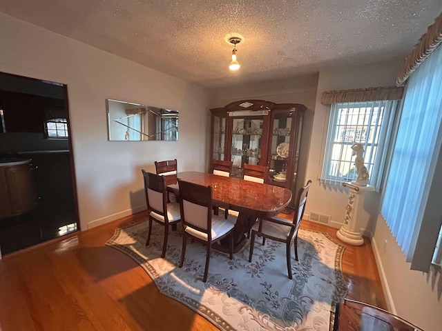 dining area featuring wood-type flooring and a textured ceiling