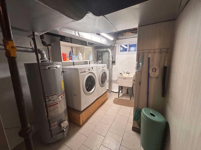 washroom with gas water heater, sink, light tile patterned flooring, and washing machine and clothes dryer