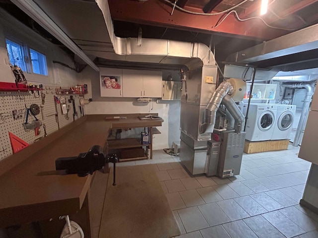 basement featuring a workshop area, heating unit, washing machine and clothes dryer, and light tile patterned floors