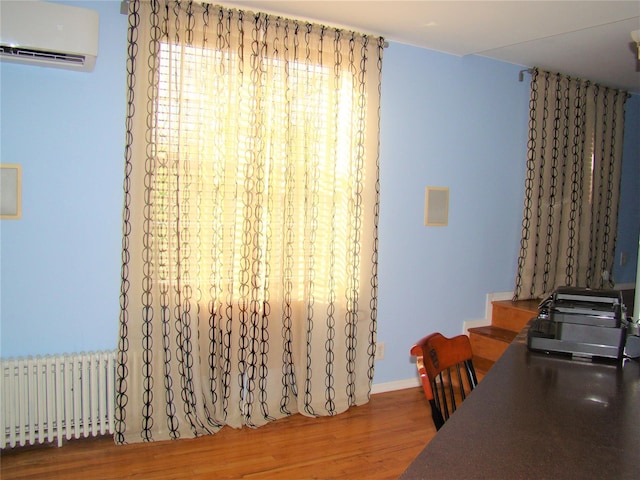 office featuring hardwood / wood-style flooring, radiator heating unit, and an AC wall unit