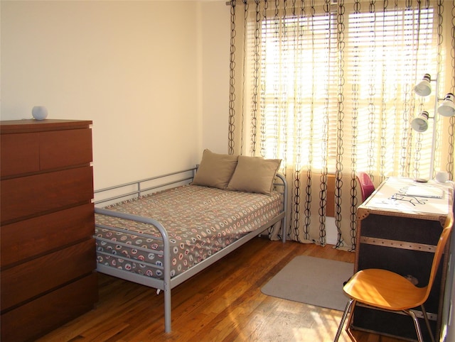 bedroom with a baseboard heating unit and wood-type flooring