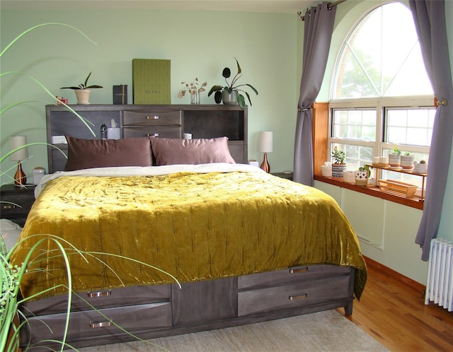 bedroom featuring radiator and hardwood / wood-style flooring