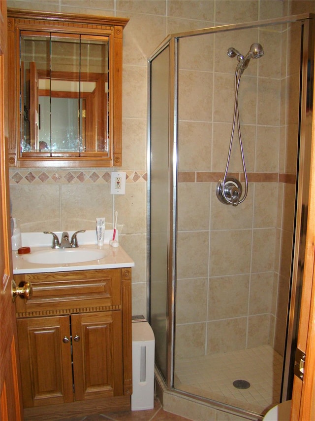 bathroom with vanity, a shower with door, and backsplash