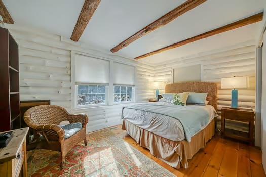 bedroom featuring beamed ceiling and light wood-type flooring