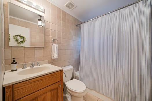 bathroom featuring tile walls, backsplash, vanity, a shower with curtain, and toilet