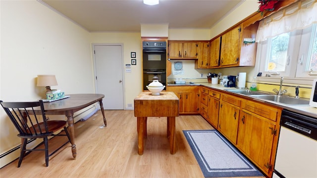 kitchen featuring dishwasher, sink, black double oven, ornamental molding, and light wood-type flooring