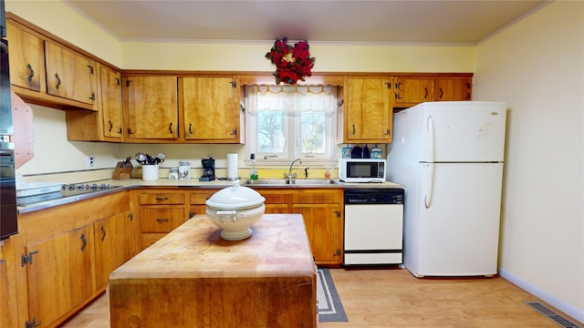 kitchen featuring white appliances, ornamental molding, sink, and a kitchen island