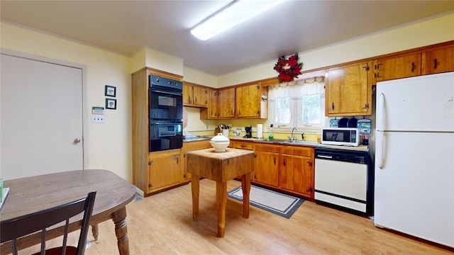 kitchen with ornamental molding, sink, white appliances, and light hardwood / wood-style flooring