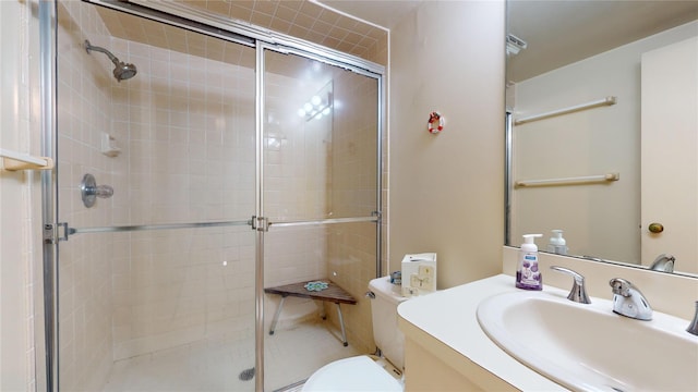 bathroom with vanity, toilet, and a shower with door