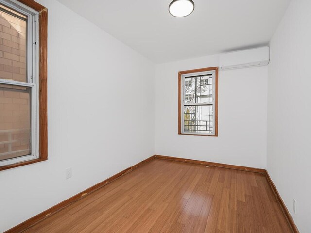 unfurnished room with a wall mounted air conditioner and wood-type flooring