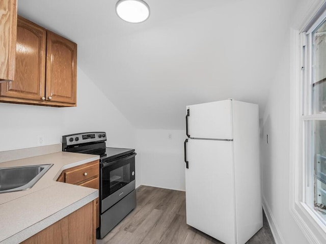 kitchen featuring lofted ceiling, sink, white fridge, light hardwood / wood-style floors, and stainless steel electric range