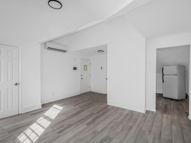 interior space with lofted ceiling, an AC wall unit, and light wood-type flooring