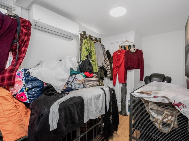 spacious closet featuring a wall unit AC and light hardwood / wood-style flooring