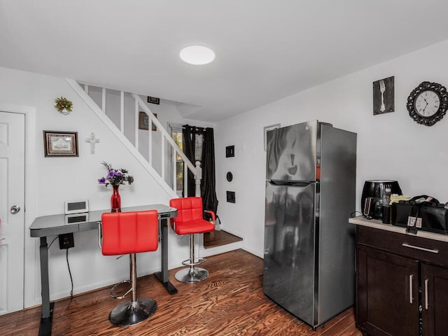 kitchen with dark brown cabinetry, dark hardwood / wood-style flooring, and stainless steel refrigerator