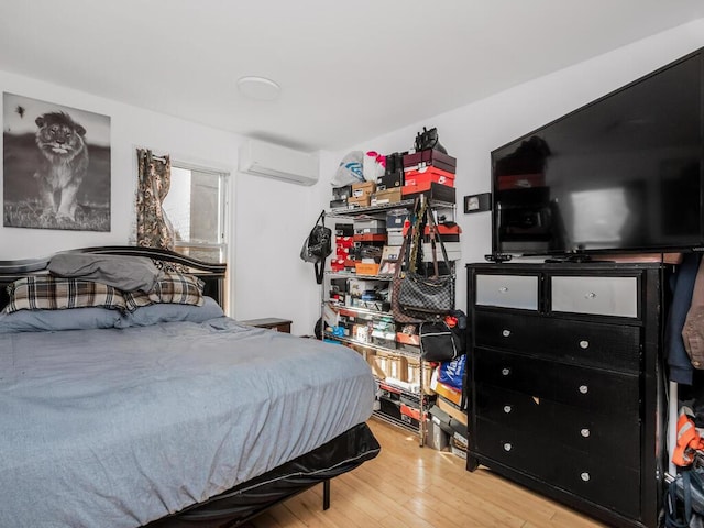 bedroom with hardwood / wood-style floors and a wall unit AC