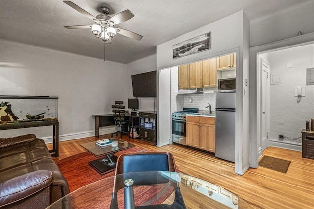 living room featuring ceiling fan, sink, and light wood-type flooring