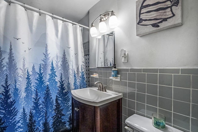 bathroom featuring walk in shower, vanity, toilet, and tile walls