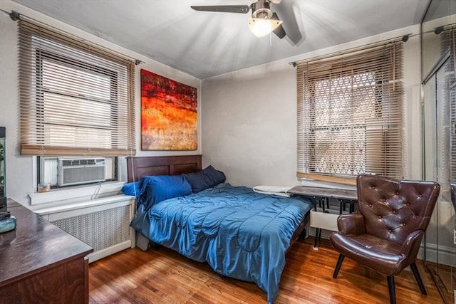 bedroom featuring cooling unit, hardwood / wood-style flooring, radiator heating unit, and ceiling fan