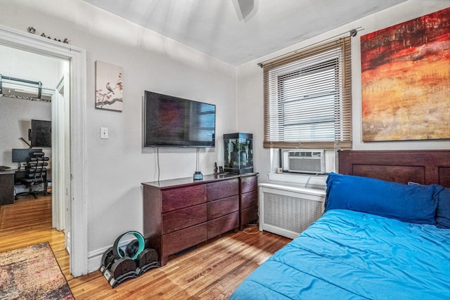 bedroom with radiator, hardwood / wood-style floors, and cooling unit