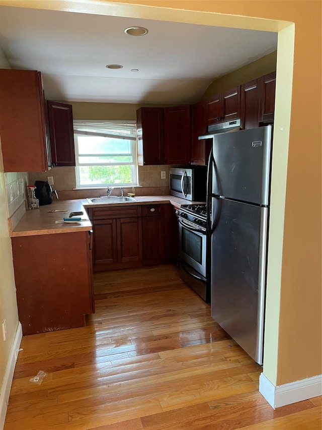 kitchen with sink, decorative backsplash, stainless steel appliances, and light wood-type flooring