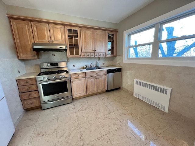 kitchen featuring tile walls, sink, radiator heating unit, and appliances with stainless steel finishes