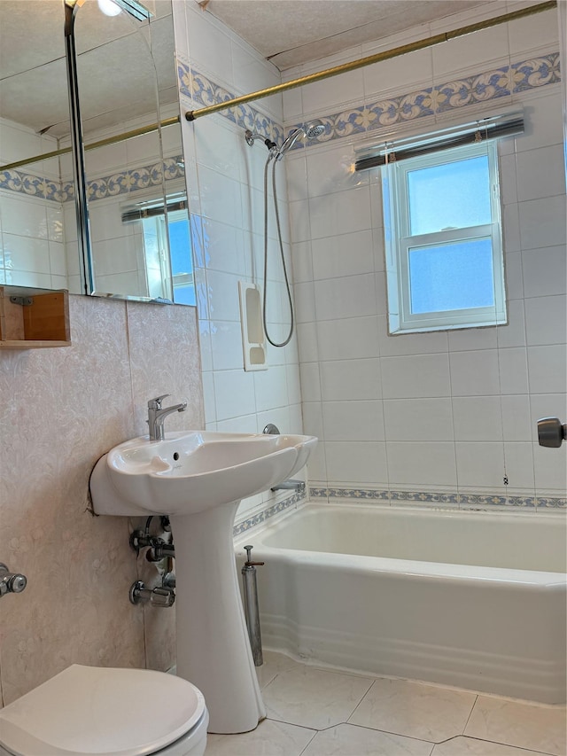 bathroom with tiled shower / bath combo, tile walls, tile patterned floors, and toilet