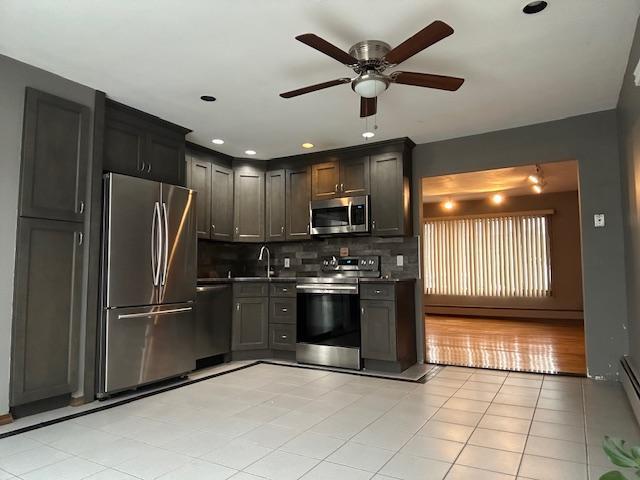 kitchen with light tile patterned flooring, sink, appliances with stainless steel finishes, ceiling fan, and backsplash