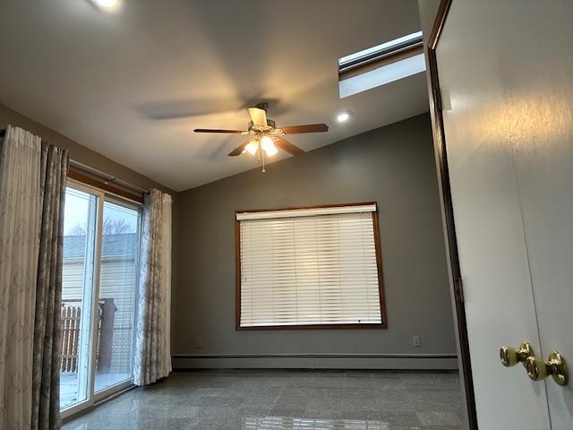 spare room featuring ceiling fan, lofted ceiling with skylight, and a baseboard heating unit