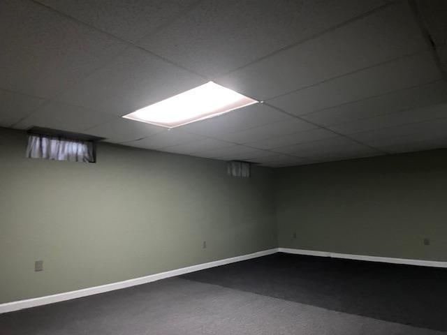 basement with a paneled ceiling and carpet flooring