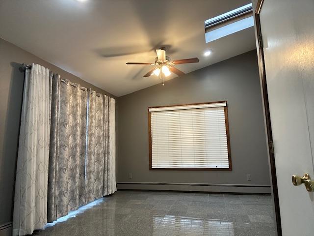 spare room featuring a baseboard radiator, lofted ceiling with skylight, and ceiling fan