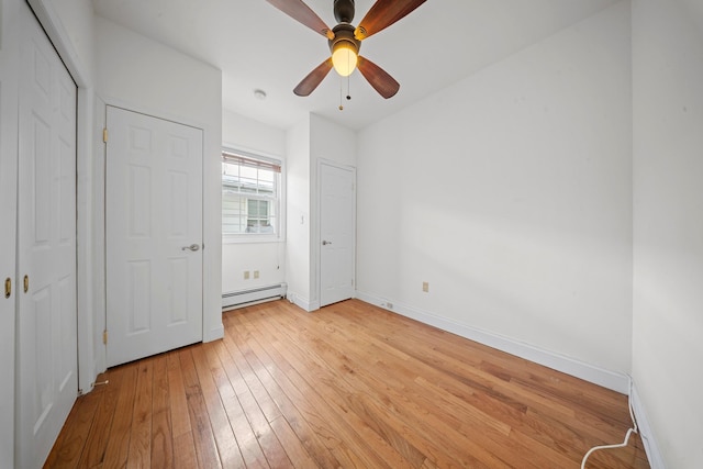 unfurnished bedroom featuring light wood-type flooring, a baseboard radiator, baseboards, and ceiling fan