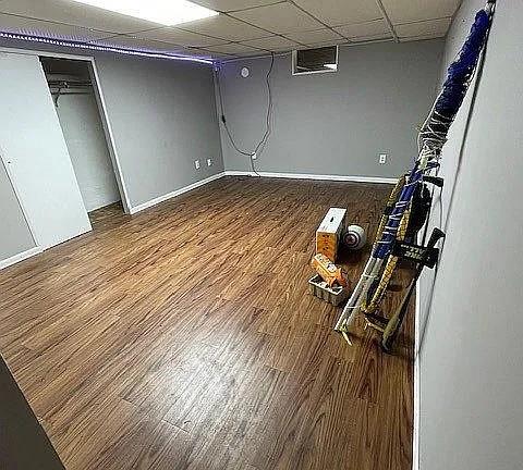 basement with wood-type flooring and a paneled ceiling