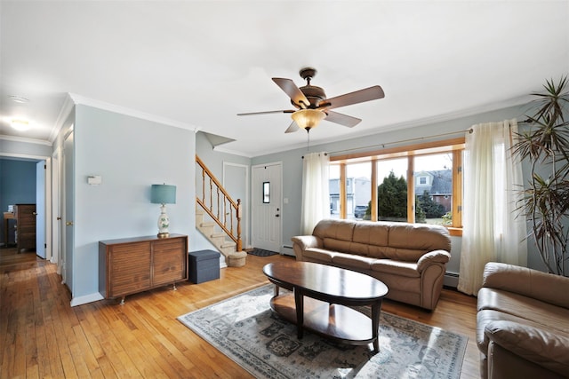 living room with ornamental molding, a baseboard heating unit, ceiling fan, and light wood-type flooring