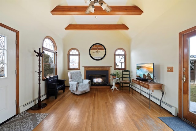 sitting room with lofted ceiling with beams, light wood-type flooring, and baseboard heating