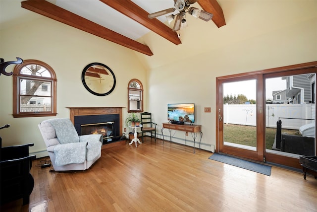 sitting room featuring ceiling fan, beam ceiling, light wood-type flooring, and a baseboard heating unit