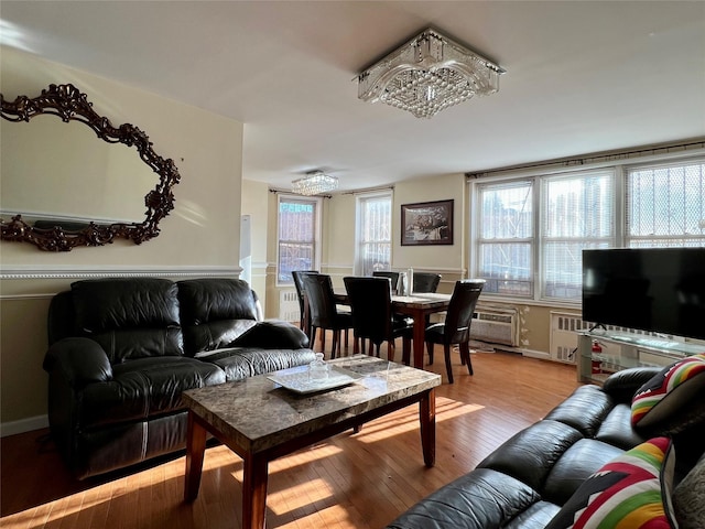 living room with an AC wall unit and light wood-type flooring