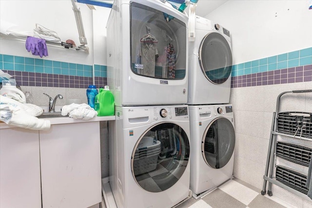 laundry room with stacked washer / dryer and tile walls