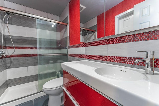 bathroom featuring toilet, a shower with shower door, sink, and tile walls