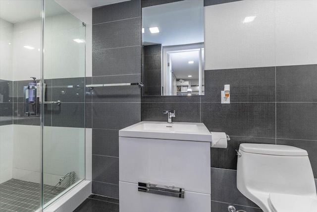 bathroom with vanity, toilet, tile walls, and walk in shower