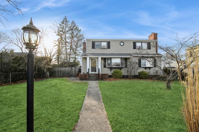 view of front of house with fence, a chimney, and a front lawn