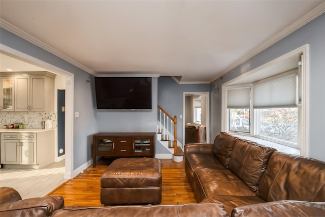 living area with ornamental molding, light wood-style floors, baseboards, and stairs