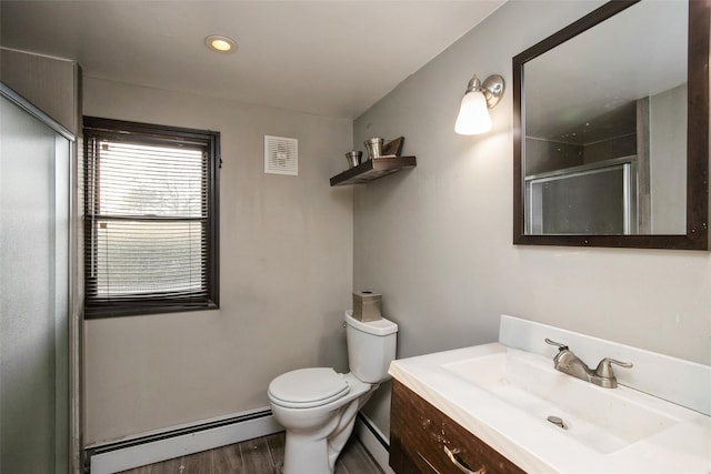 bathroom featuring toilet, a baseboard heating unit, wood finished floors, vanity, and a stall shower