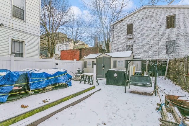 yard covered in snow with a swimming pool and a shed