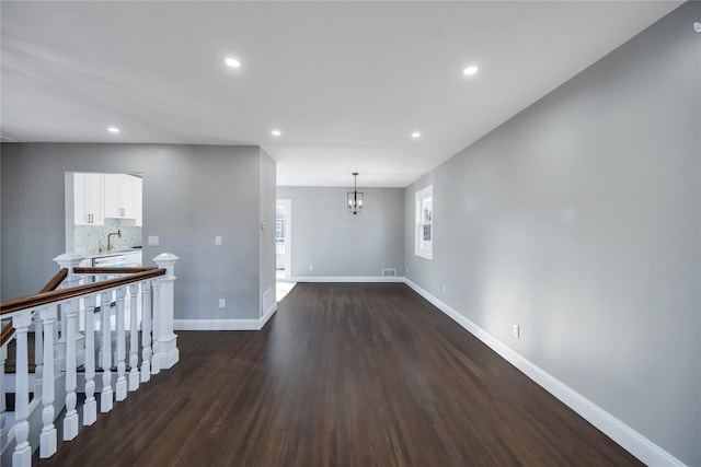 unfurnished room featuring sink, a notable chandelier, and dark hardwood / wood-style floors