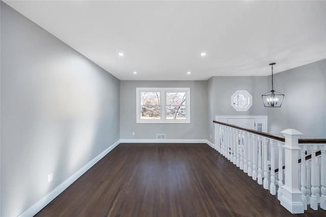 unfurnished room featuring dark hardwood / wood-style flooring and a notable chandelier