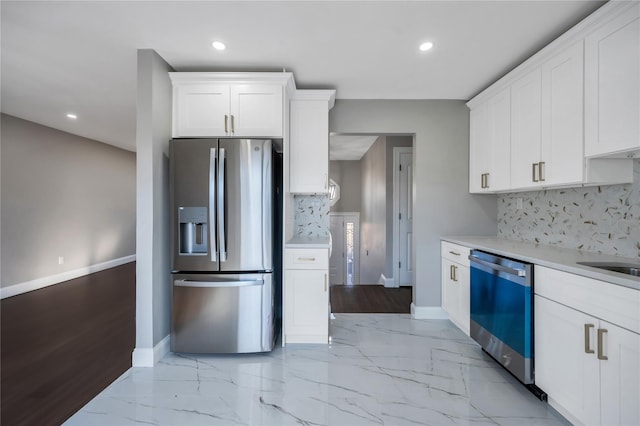 kitchen featuring stainless steel appliances, white cabinetry, and backsplash