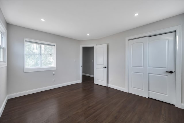 unfurnished bedroom with dark hardwood / wood-style flooring and a closet