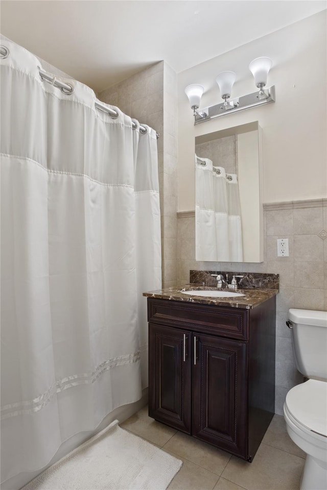 bathroom with tile walls, vanity, tile patterned floors, and toilet