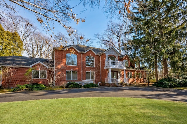 view of front facade featuring a balcony and a front yard